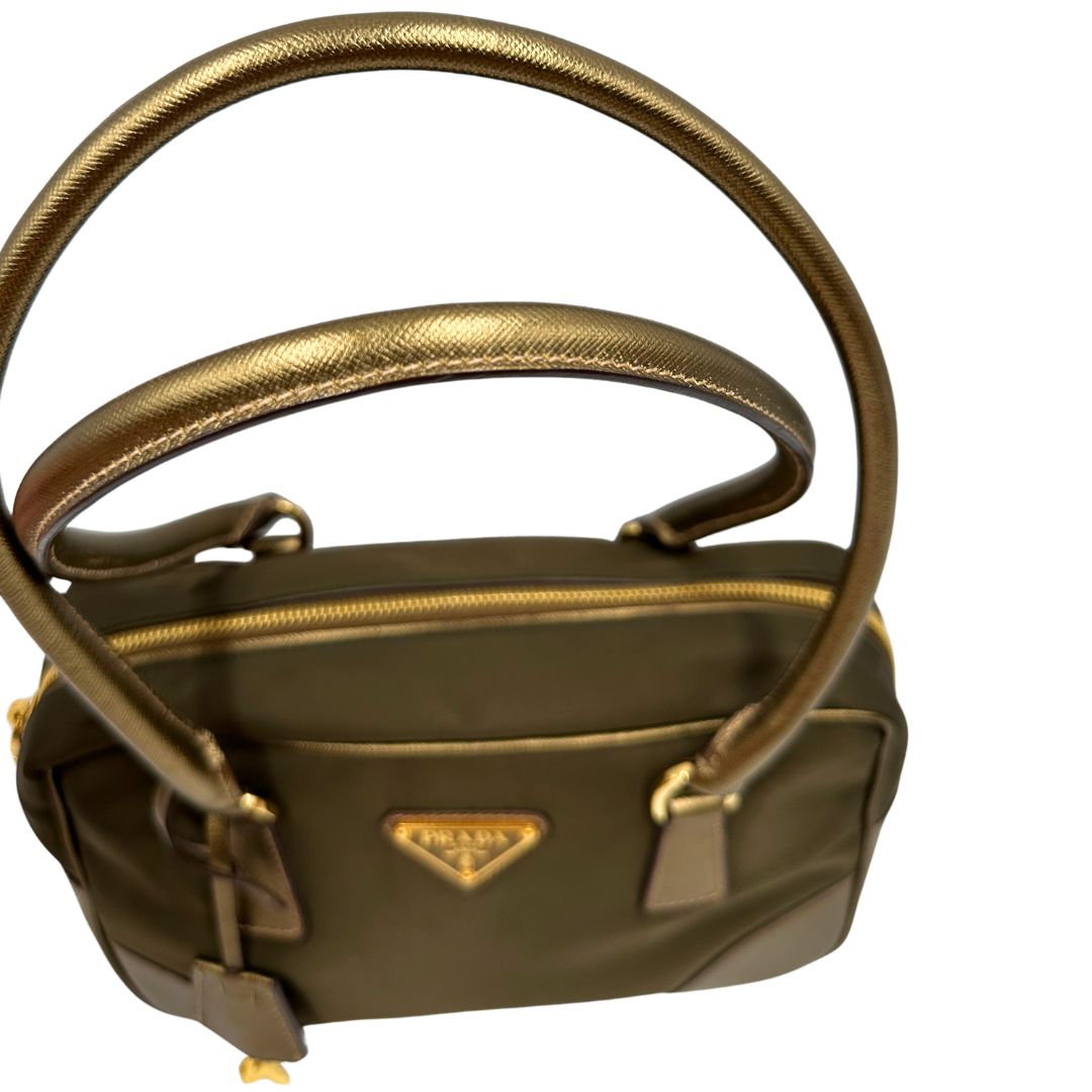 Manici di un bauletto Prada in tessuto nylon e pelle saffiano bronzo, con dettagli metallici dorati, indossabile a spalla, usato, originale, second hand, in ottime condizioni.