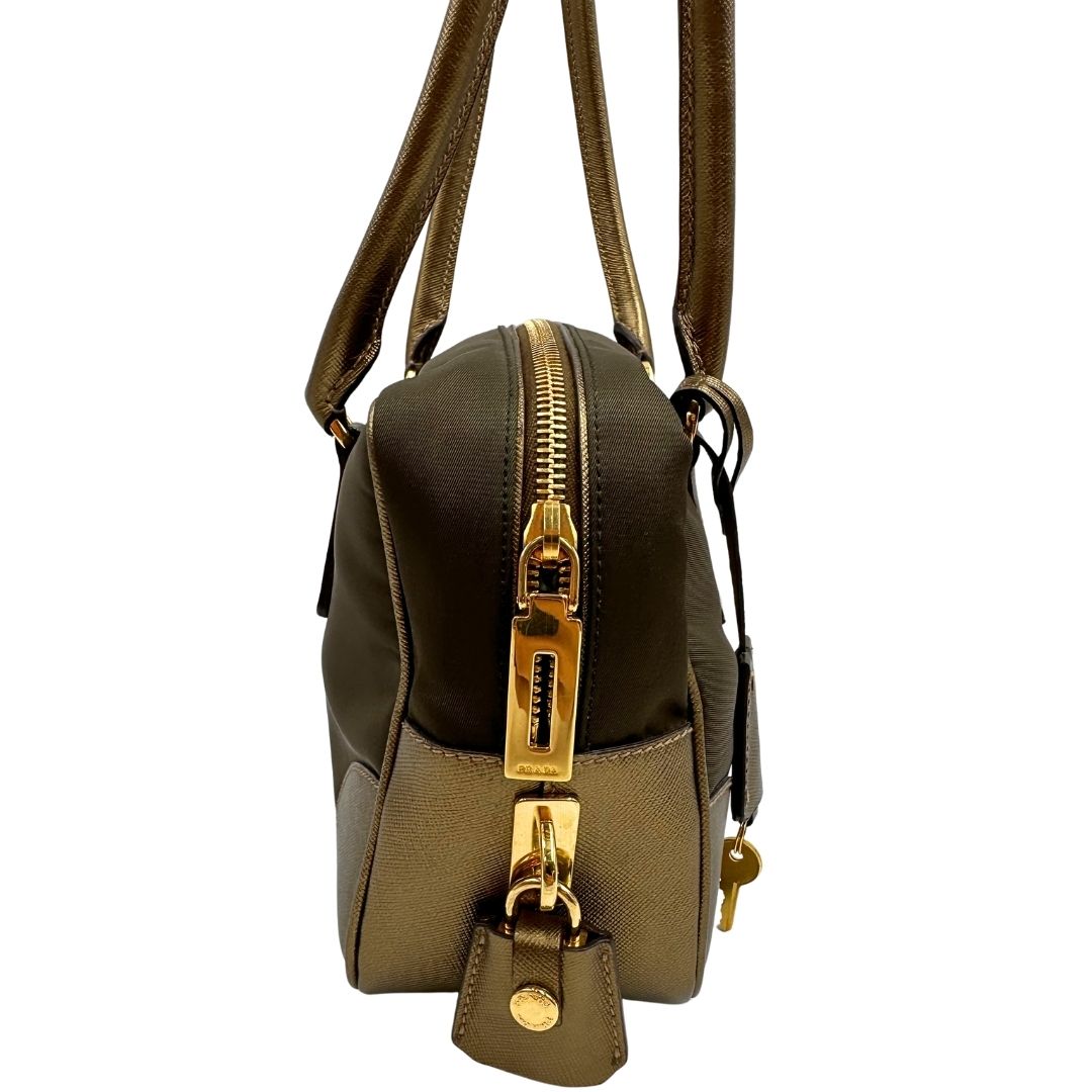 Vista laterale di un bauletto Prada in tessuto nylon e pelle saffiano bronzo, con dettagli metallici dorati, indossabile a spalla, usato, originale, second hand, in ottime condizioni.