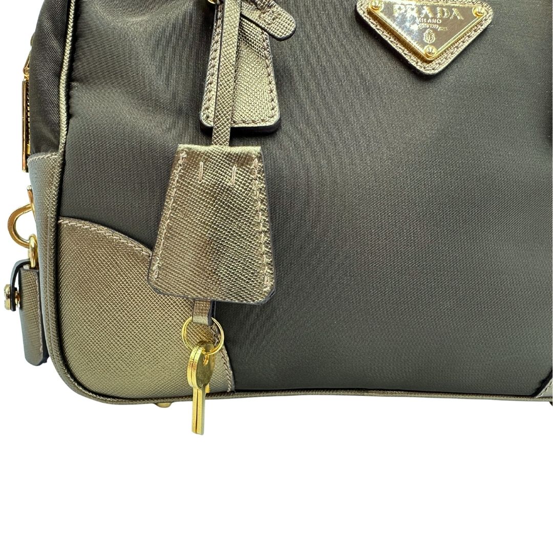 Clochette portachiavi di un bauletto Prada in tessuto nylon e pelle saffiano bronzo, con dettagli metallici dorati, indossabile a spalla, usato, originale, second hand, in ottime condizioni.