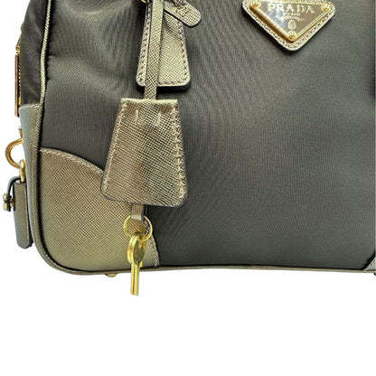 Clochette portachiavi di un bauletto Prada in tessuto nylon e pelle saffiano bronzo, con dettagli metallici dorati, indossabile a spalla, usato, originale, second hand, in ottime condizioni.