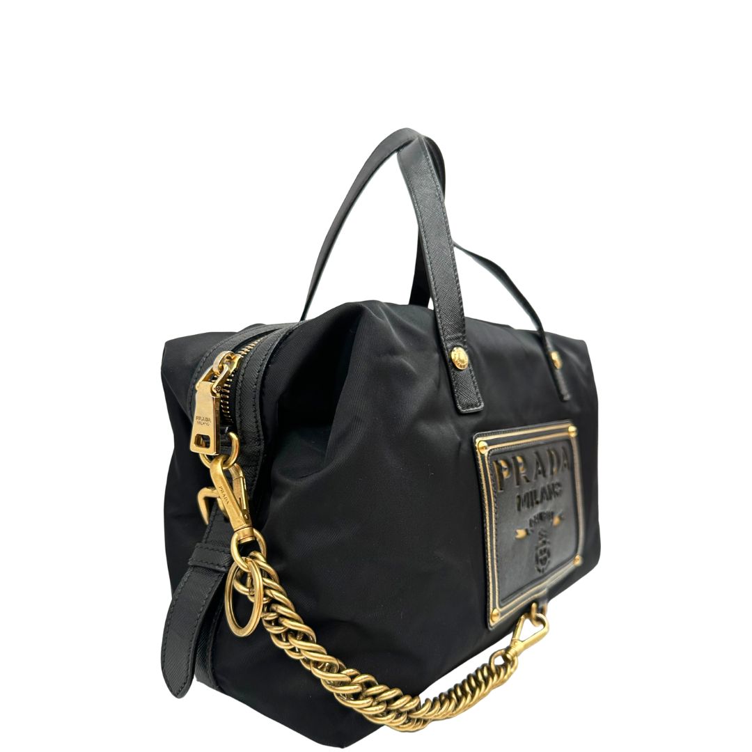 Laterale sinistro di un bauletto Prada in tessuto vela e dettagli dorati, indossabile a mano, usato, originale, second hand, in ottime condizioni.