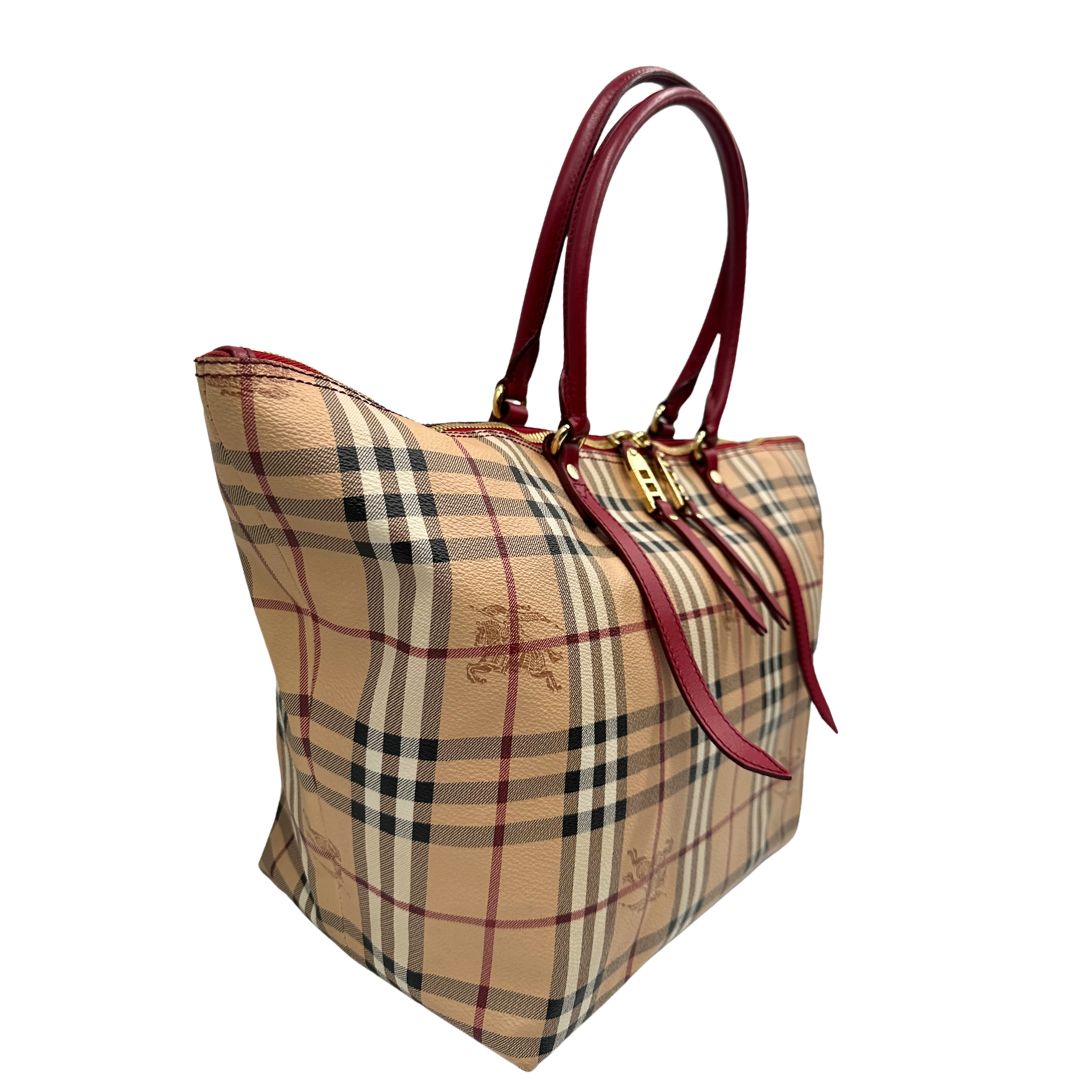 Laterale sinistro di una shopper Burberry in canvas trama tartan con finiture in pelle bordeaux, usata, originale, second hand, in ottime condizioni.