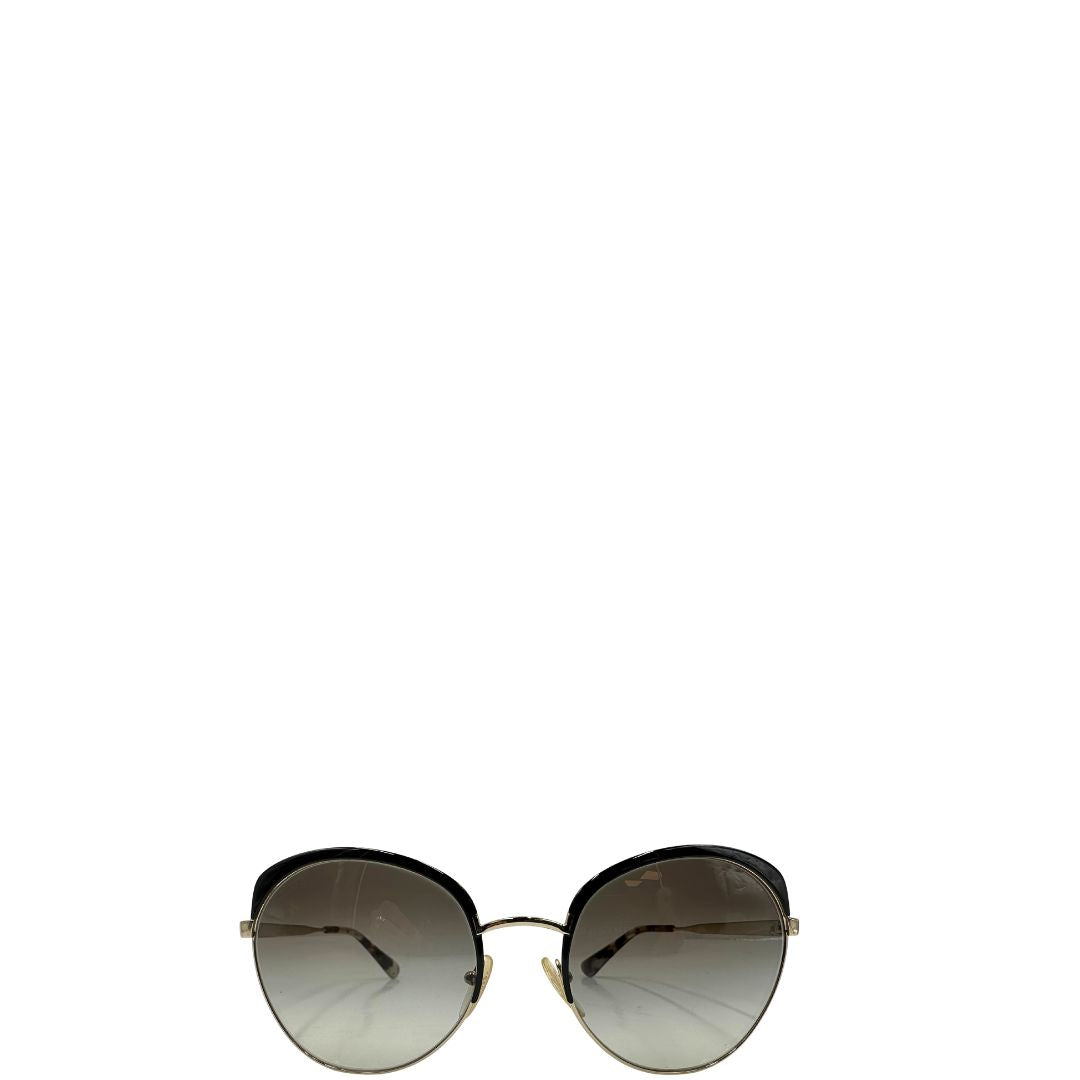 Front di un paio di occhiali da sole Prada caratterizzati da una montatura nera lucida con lenti sfumate grigie, asticelle maculate e hardware dorato, usati, originali, second hand, in ottime condizioni.