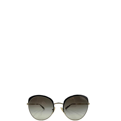 Front di un paio di occhiali da sole Prada caratterizzati da una montatura nera lucida con lenti sfumate grigie, asticelle maculate e hardware dorato, usati, originali, second hand, in ottime condizioni.