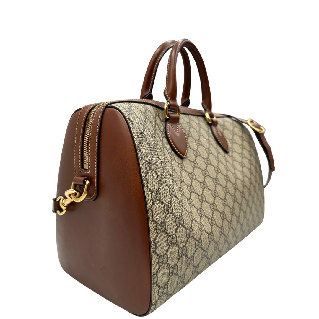 Laterale sinistro di un bauletto Gucci GG in canvas beige, con parti in pelle marroni, usato, originale, second hand, in ottime condizioni.