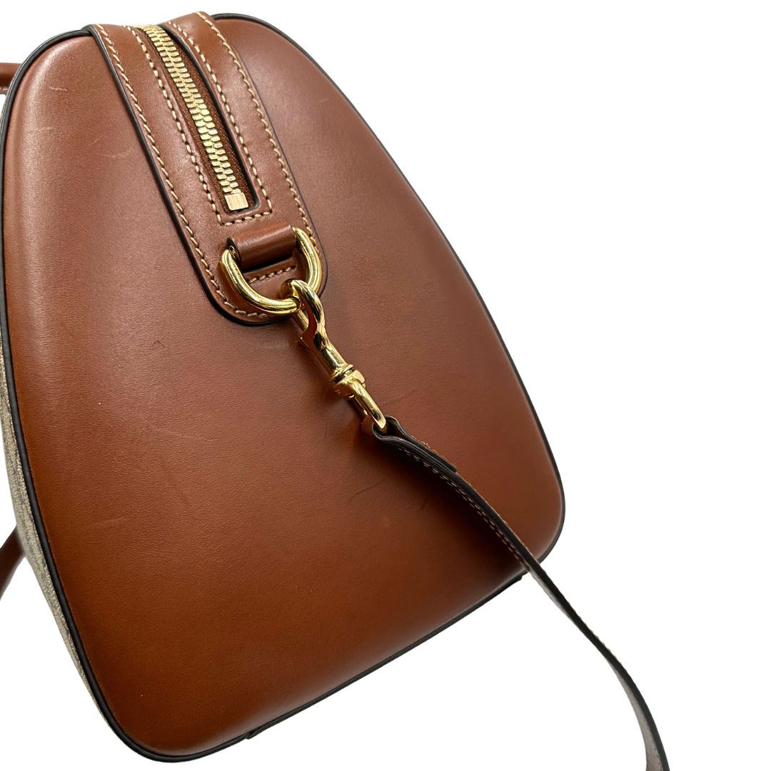 Vista laterale di un bauletto Gucci GG in canvas beige, con parti in pelle marroni, usato, originale, second hand, in ottime condizioni.