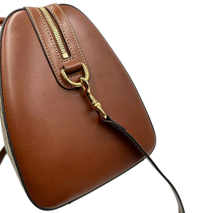 Vista laterale di un bauletto Gucci GG in canvas beige, con parti in pelle marroni, usato, originale, second hand, in ottime condizioni.