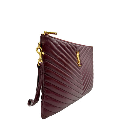 Laterale sinistro di una pochette Saint Laurent in pelle bordeaux trapuntata, con parti metalliche dorate, usata, originale, second hand, in ottime condizioni.