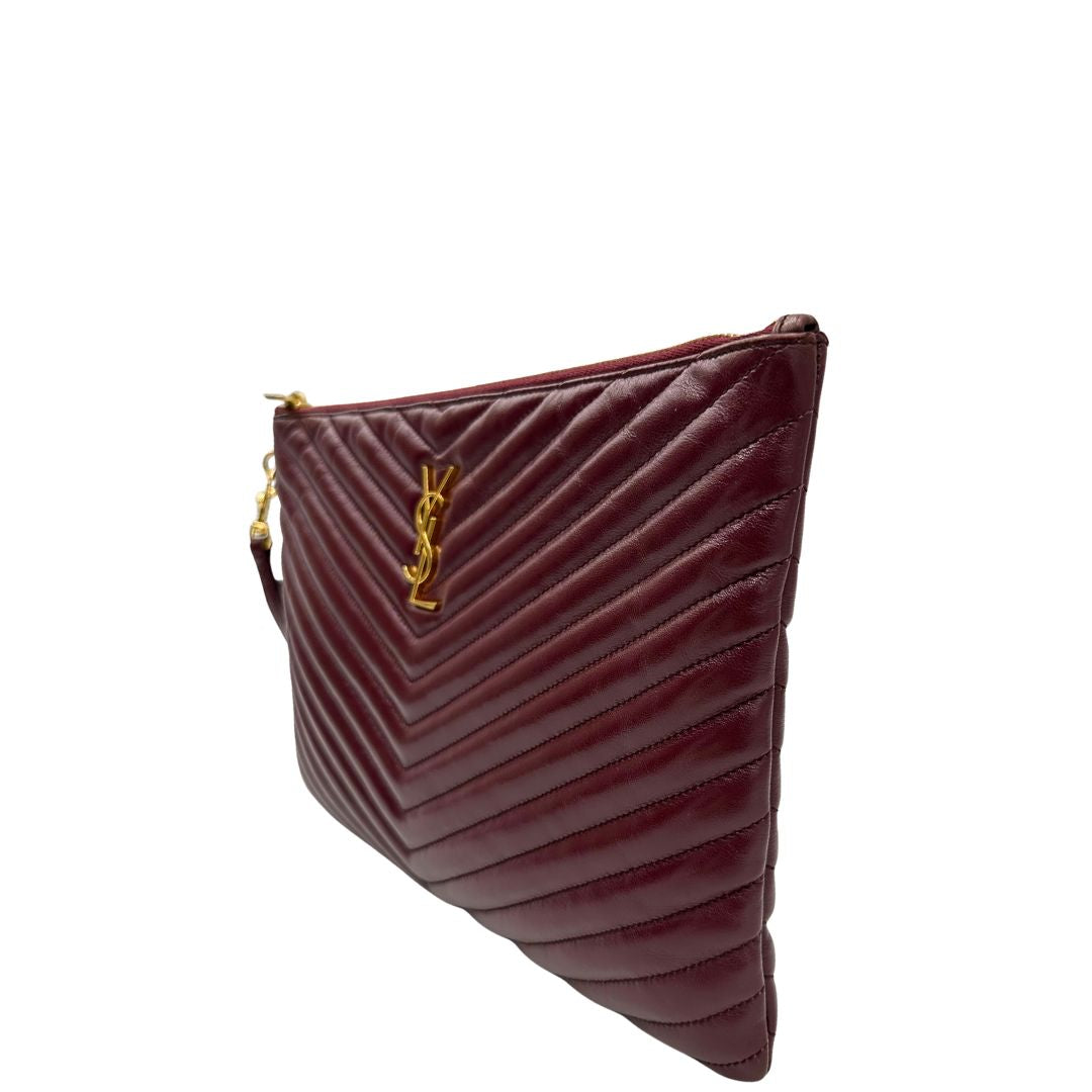 Laterale destro di una pochette Saint Laurent in pelle bordeaux trapuntata, con parti metalliche dorate, usata, originale, second hand, in ottime condizioni.