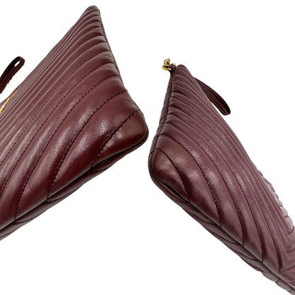 Angoli di una pochette Saint Laurent in pelle bordeaux trapuntata, con parti metalliche dorate, usata, originale, second hand, in ottime condizioni.