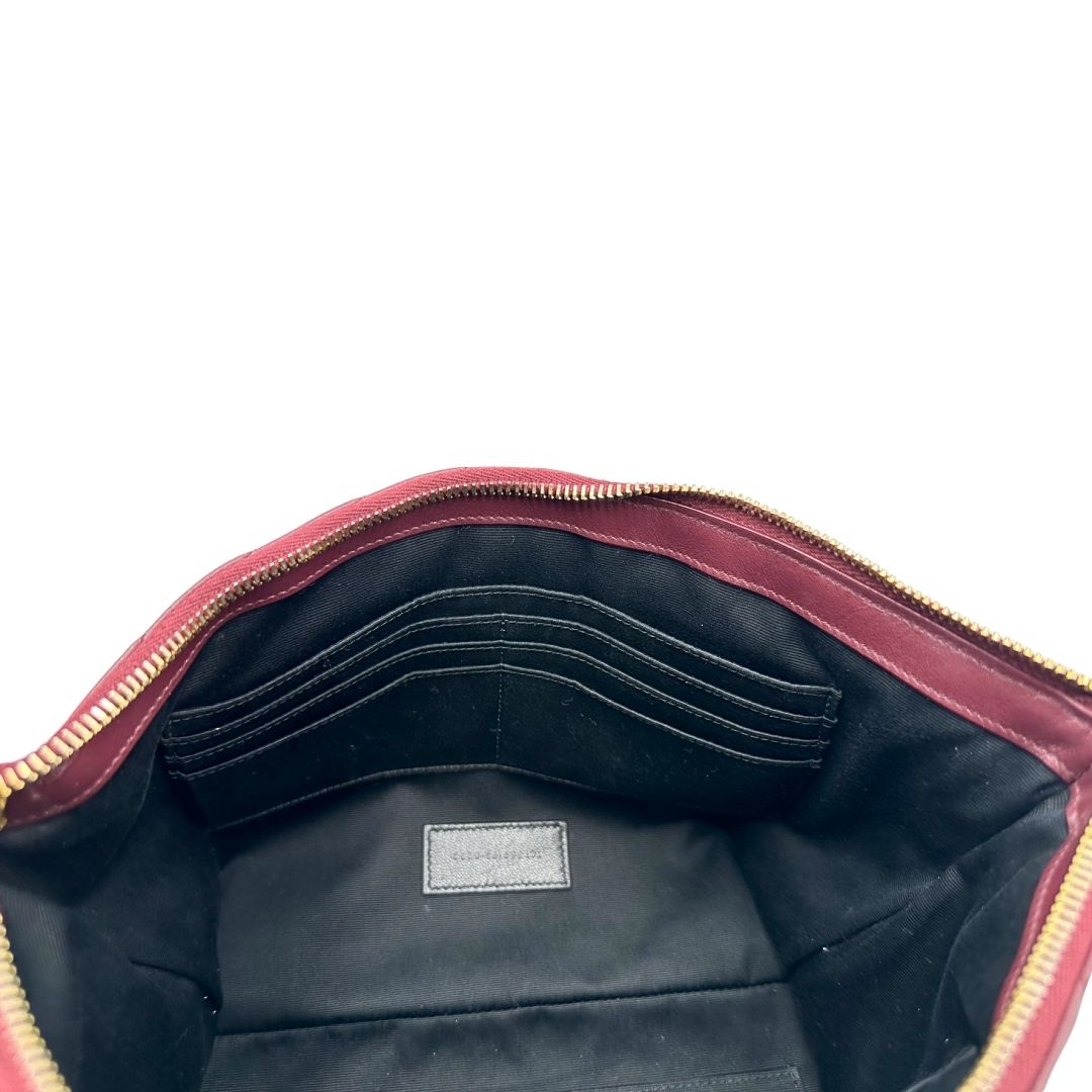 Interno di una pochette Saint Laurent in pelle bordeaux trapuntata, con parti metalliche dorate, usata, originale, second hand, in ottime condizioni.