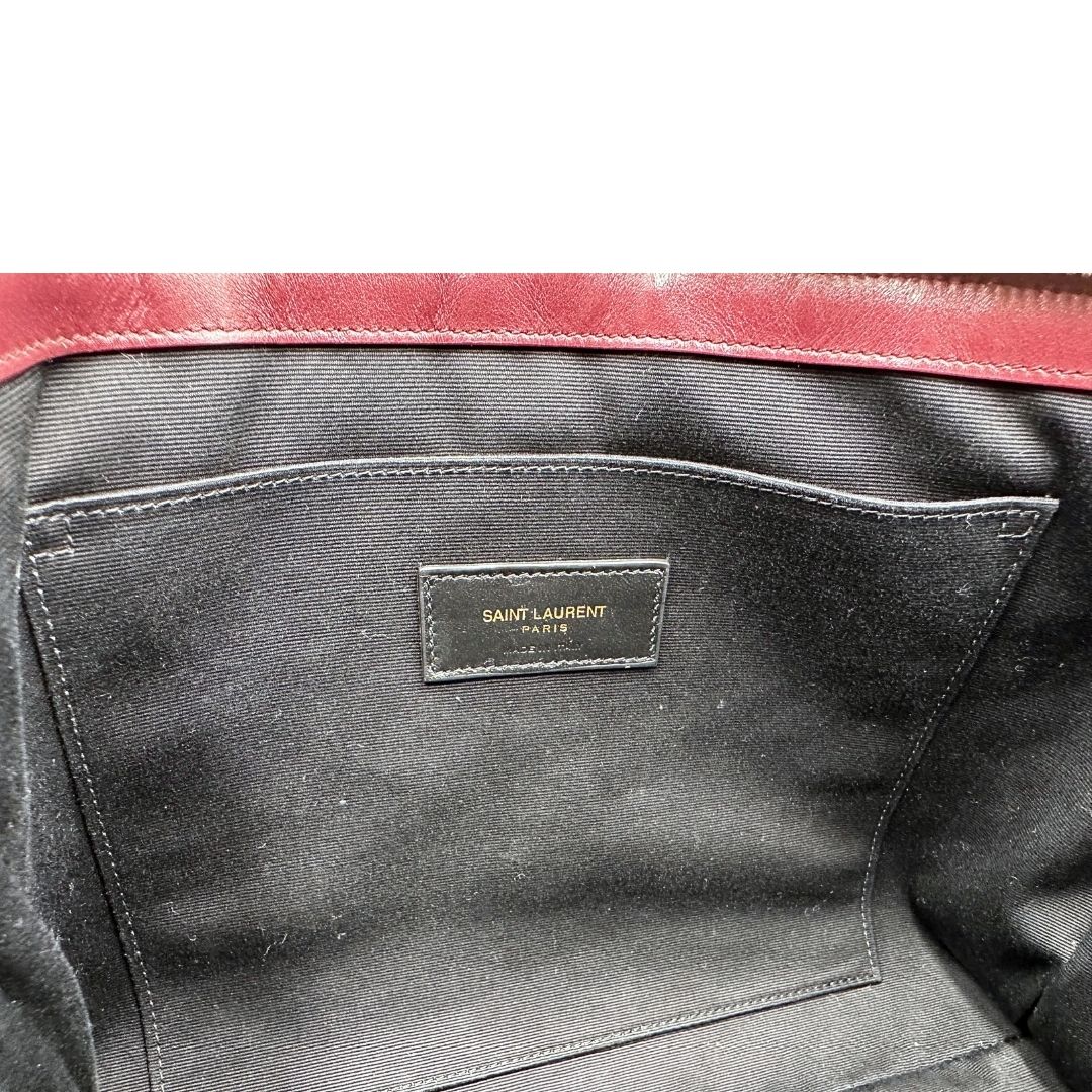 Interno di una pochette Saint Laurent in pelle bordeaux trapuntata, con parti metalliche dorate, usata, originale, second hand, in ottime condizioni.