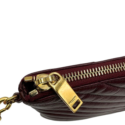 Tirante di una pochette Saint Laurent in pelle bordeaux trapuntata, con parti metalliche dorate, usata, originale, second hand, in ottime condizioni.