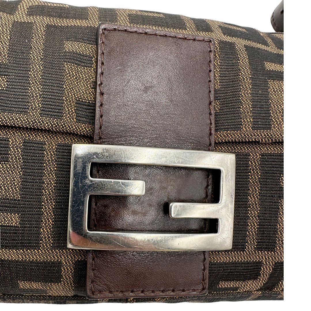 Logo di una borsa Fendi Baguette marrone in tessuto trama Zucca, indossabile a spalla, usata, originale, second hand, in ottime condizioni.