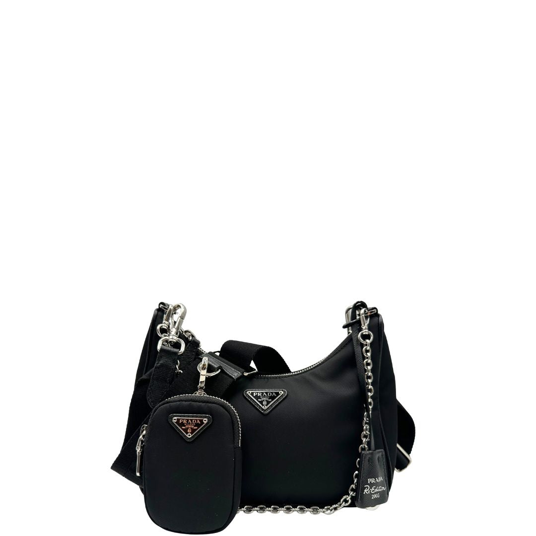 Front di una borsa Prada Re-Edition 2005 in nylon nero con dettagli in pelle e hardware argento, arricchita da catena frontale, mini pouch removibile e portachiavi logato. Modello compatto e versatile, utilizzabile a spalla, a mano o crossbody, usata, originale, second hand, in condizioni eccellenti.