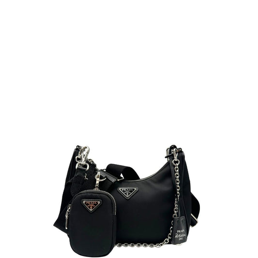 Front di una borsa Prada Re-Edition 2005 in nylon nero con dettagli in pelle e hardware argento, arricchita da catena frontale, mini pouch removibile e portachiavi logato. Modello compatto e versatile, utilizzabile a spalla, a mano o crossbody, usata, originale, second hand, in condizioni eccellenti.