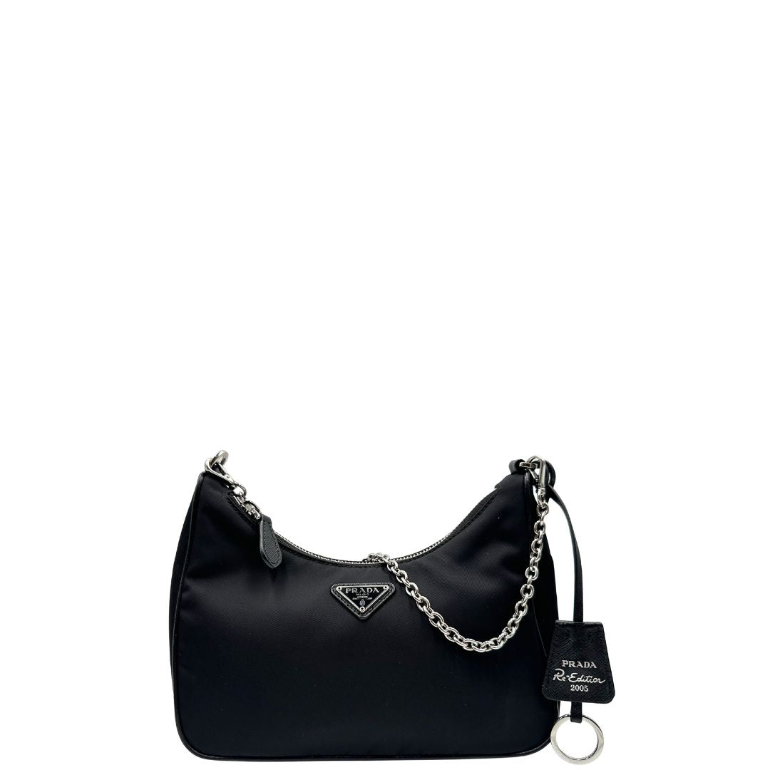 Front di una borsa Prada Re-Edition 2005 in nylon nero con dettagli in pelle e hardware argento, arricchita da catena frontale, mini pouch removibile e portachiavi logato. Modello compatto e versatile, utilizzabile a spalla, a mano o crossbody, usata, originale, second hand, in condizioni eccellenti.