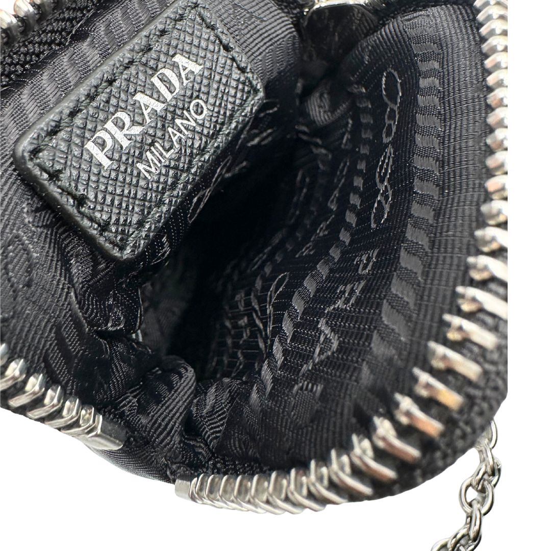 Interno di una pouch amovibile di una borsa Prada Re-Edition 2005 in nylon nero con dettagli in pelle e hardware argento, arricchita da catena frontale e portachiavi logato. Modello compatto e versatile, utilizzabile a spalla, a mano o crossbody, usata, originale, second hand, in condizioni eccellenti.