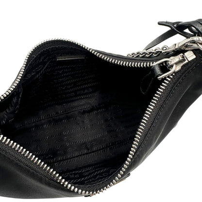 Interno di una borsa Prada Re-Edition 2005 in nylon nero con dettagli in pelle e hardware argento, arricchita da catena frontale, mini pouch removibile e portachiavi logato. Modello compatto e versatile, utilizzabile a spalla, a mano o crossbody, usata, originale, second hand, in condizioni eccellenti.