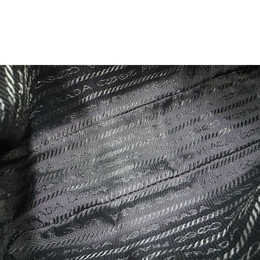 Interno di una borsa Prada Re-Edition 2005 in nylon nero con dettagli in pelle e hardware argento, arricchita da catena frontale, mini pouch removibile e portachiavi logato. Modello compatto e versatile, utilizzabile a spalla, a mano o crossbody, usata, originale, second hand, in condizioni eccellenti.