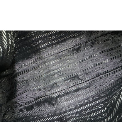 Interno di una borsa Prada Re-Edition 2005 in nylon nero con dettagli in pelle e hardware argento, arricchita da catena frontale, mini pouch removibile e portachiavi logato. Modello compatto e versatile, utilizzabile a spalla, a mano o crossbody, usata, originale, second hand, in condizioni eccellenti.