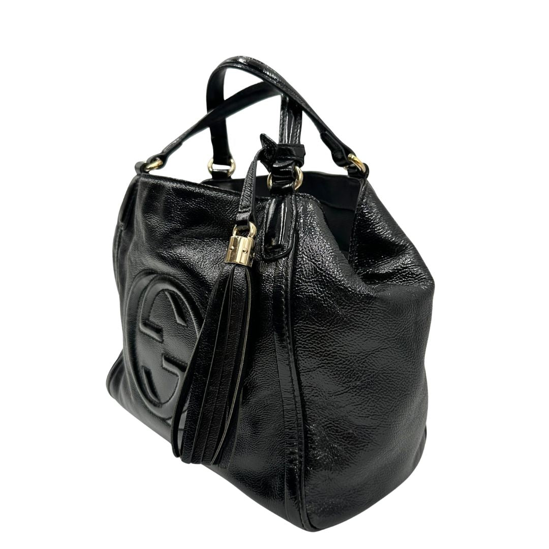 Lati sinistro, Borsa Gucci Soho in pelle verniciata nera con logo Soho in rilievo e parti metalliche dorate; da indossare a mano oppure a mano. Originale, usata, di lusso, in ottime condizioni.