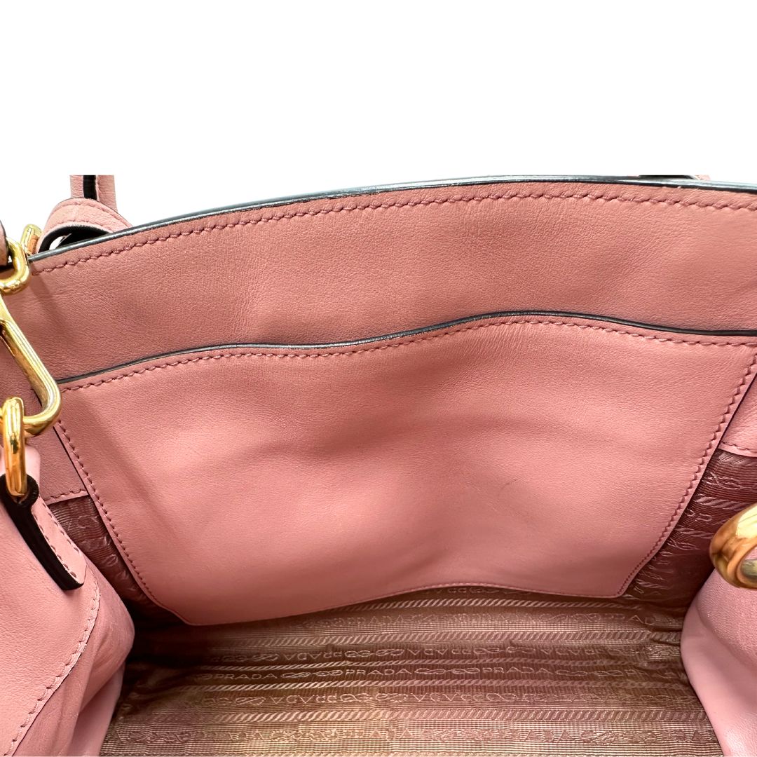 Interno di una borsa Prada rosa in pelle saffiano, dotata di un pratico charm con specchietto amovibile, usata, originale, second hand, in ottime condizioni.