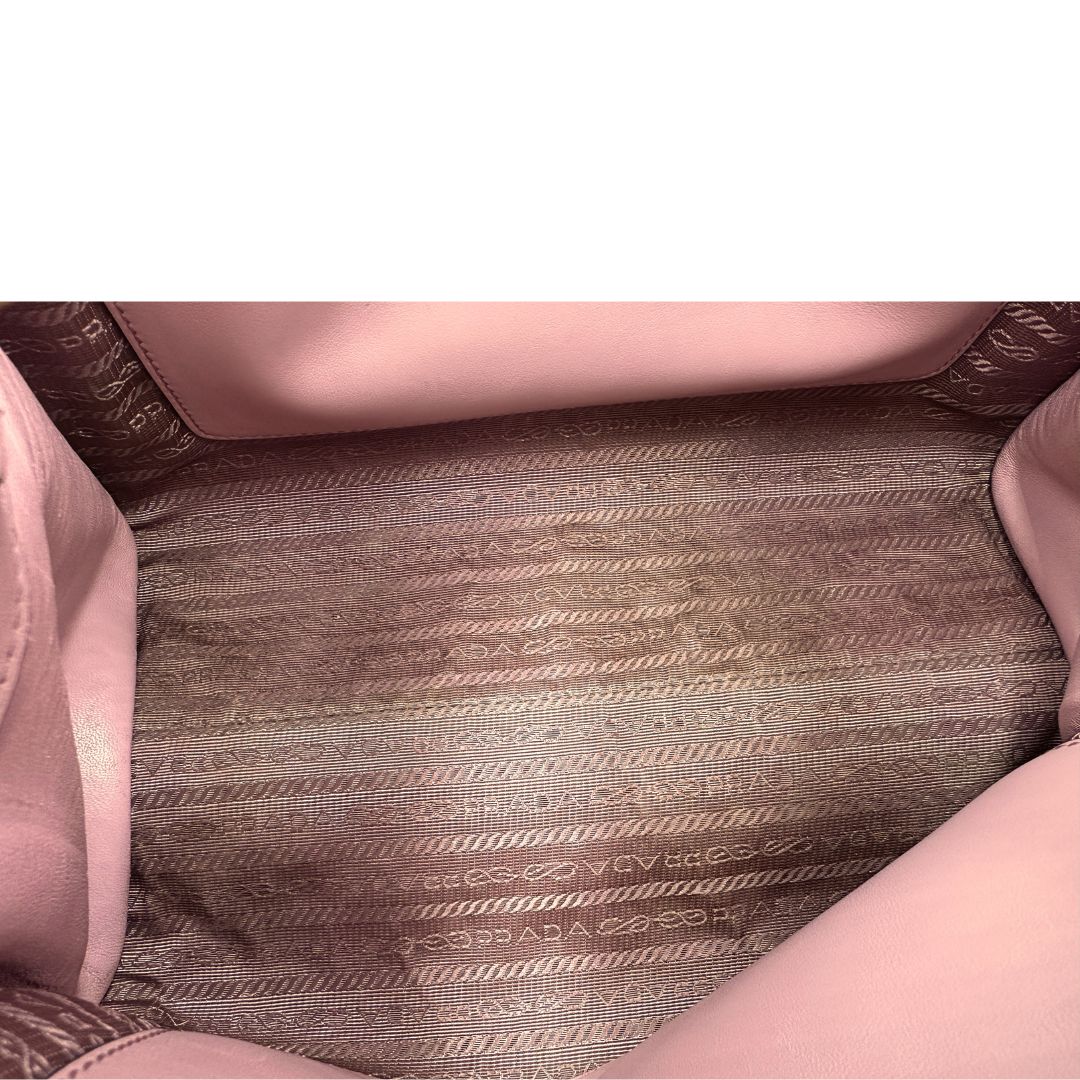 Interno di una borsa Prada rosa in pelle saffiano, dotata di un pratico charm con specchietto amovibile, usata, originale, second hand, in ottime condizioni.