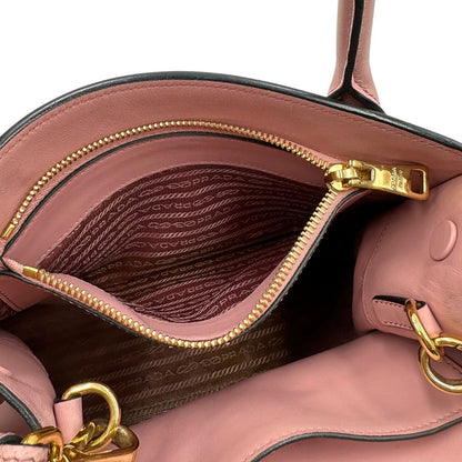 Interno di una borsa Prada rosa in pelle saffiano, dotata di un pratico charm con specchietto amovibile, usata, originale, second hand, in ottime condizioni.