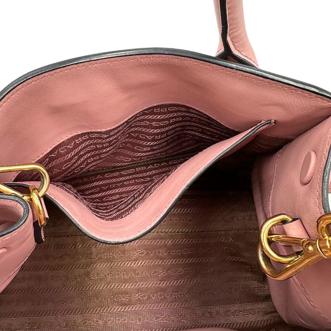 Interno di una borsa Prada rosa in pelle saffiano, dotata di un pratico charm con specchietto amovibile, usata, originale, second hand, in ottime condizioni.