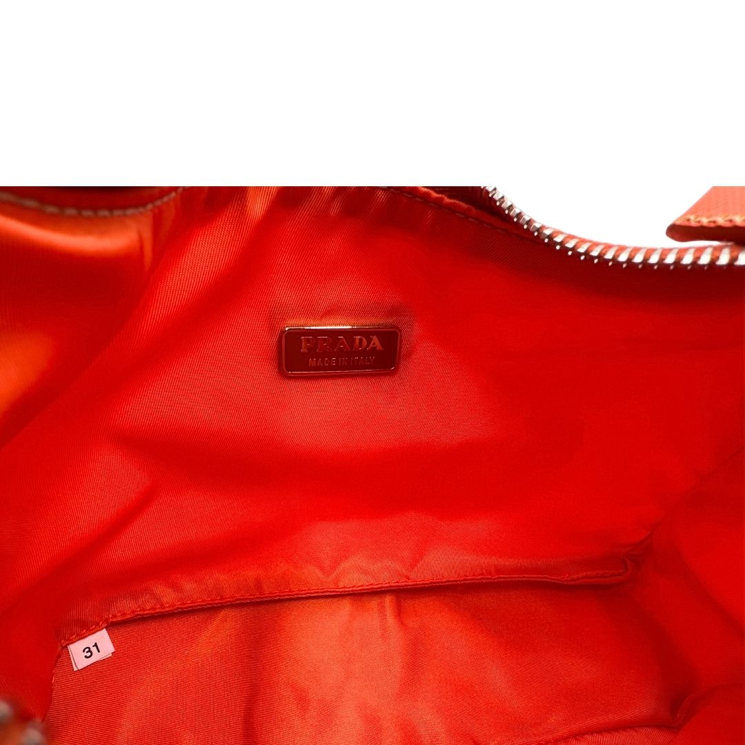 Interno di una borsa a spalla Prada in nylon arancione con dettagli in pelle Saffiano tono su tono e parti metalliche argentate, usata, originale, second hand, in condizioni eccellenti.