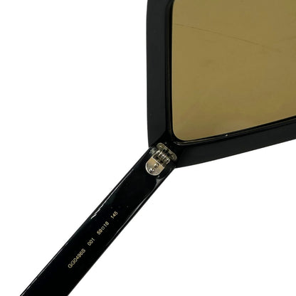 Occhiali Gucci unisex caratterizzati da una distintiva montatura geometrica a forma di diamante, realizzati in acetato nero lucido con lenti color giallo scuro.