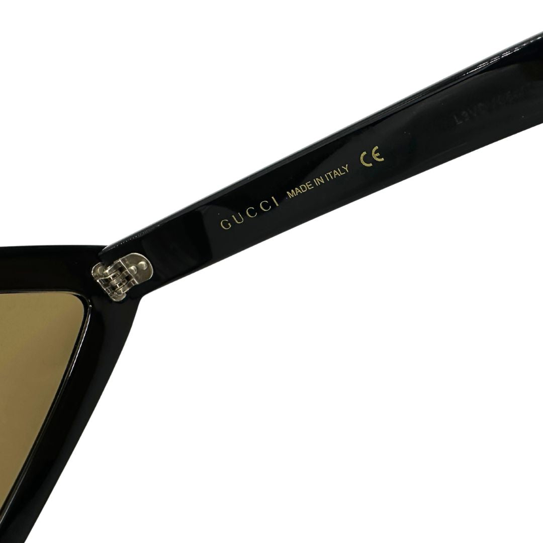 Occhiali Gucci unisex caratterizzati da una distintiva montatura geometrica a forma di diamante, realizzati in acetato nero lucido con lenti color giallo scuro.