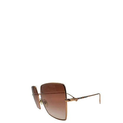 Occhiali da sole Burberry in metallo dorato con una montatura squadrata oversize in metallo, lenti sfumate marroni o rosa.