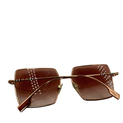 Occhiali da sole Burberry in metallo dorato con una montatura squadrata oversize in metallo, lenti sfumate marroni o rosa.