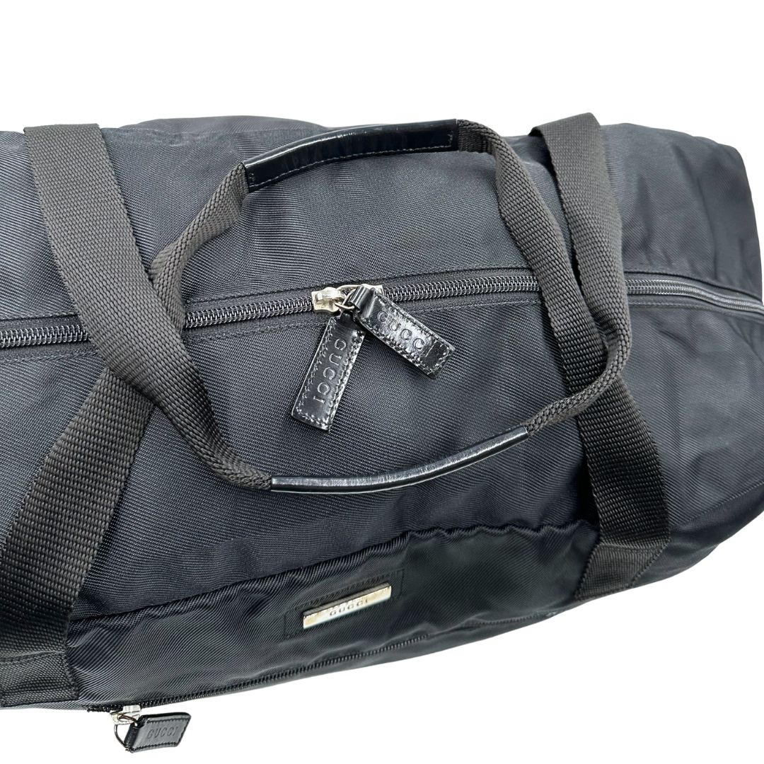 Chiusura di un borsone Gucci in tela nera, con dettagli in pelle tono su tono, usato, originale, second hand, in ottime condizioni.