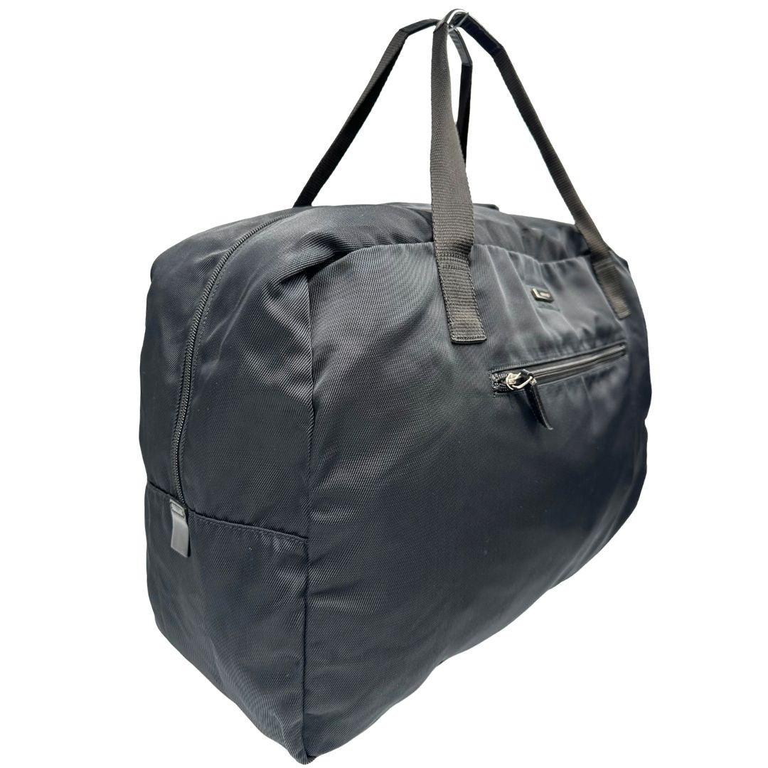 Laterale sinistro di un borsone Gucci in tela nera, con dettagli in pelle tono su tono, usato, originale, second hand, in ottime condizioni.