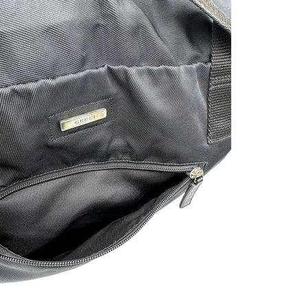 Apertura della zip frontale di un borsone Gucci in tela nera, con dettagli in pelle tono su tono, usato, originale, second hand, in ottime condizioni.