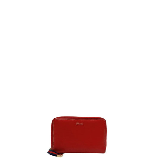 Front di un portafoglio Gucci in pelle rossa, con tirante in tessuto in iconica trama Web rossa e blu, impreziosito da parti metalliche dorate, usato, originali, second hand, in ottime condizioni.