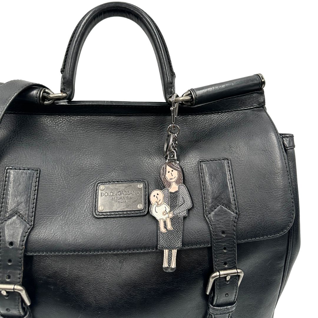 Borsa da viaggio D&G realizzata in pelle nera con hardware argentato anticato e charms decorativi. Indossabile a mano oppure a tracolla. Originale, usata, di lusso, in ottime condizioni.