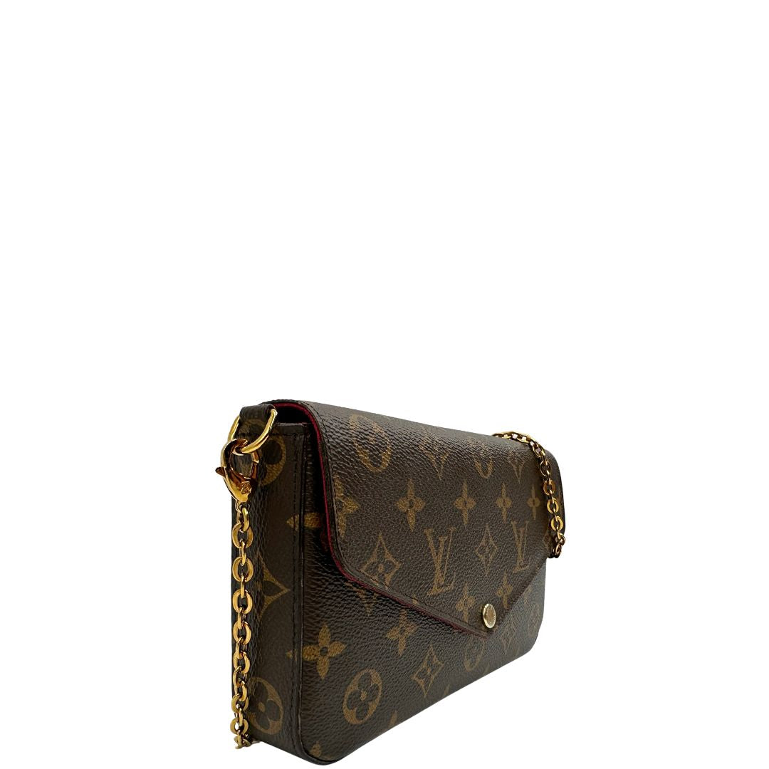 Laterale sinistro di una tracolla Louis Vuitton in canvas marrone monogram ed amaranto, con parti metalliche dorate. Munita di una tracolla in catena amovibile, ma non regolabile e di accessori estraibili portamonete e portacarte, usata, originale, second hand, in ottime condizioni.