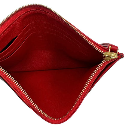 Interno di una pochette Louis Vuitton con scomparti interni portacarte, in canvas marrone monogram e dettagli rossi, con parti metalliche dorate, usata, originale, second hand, in ottime condizioni.
