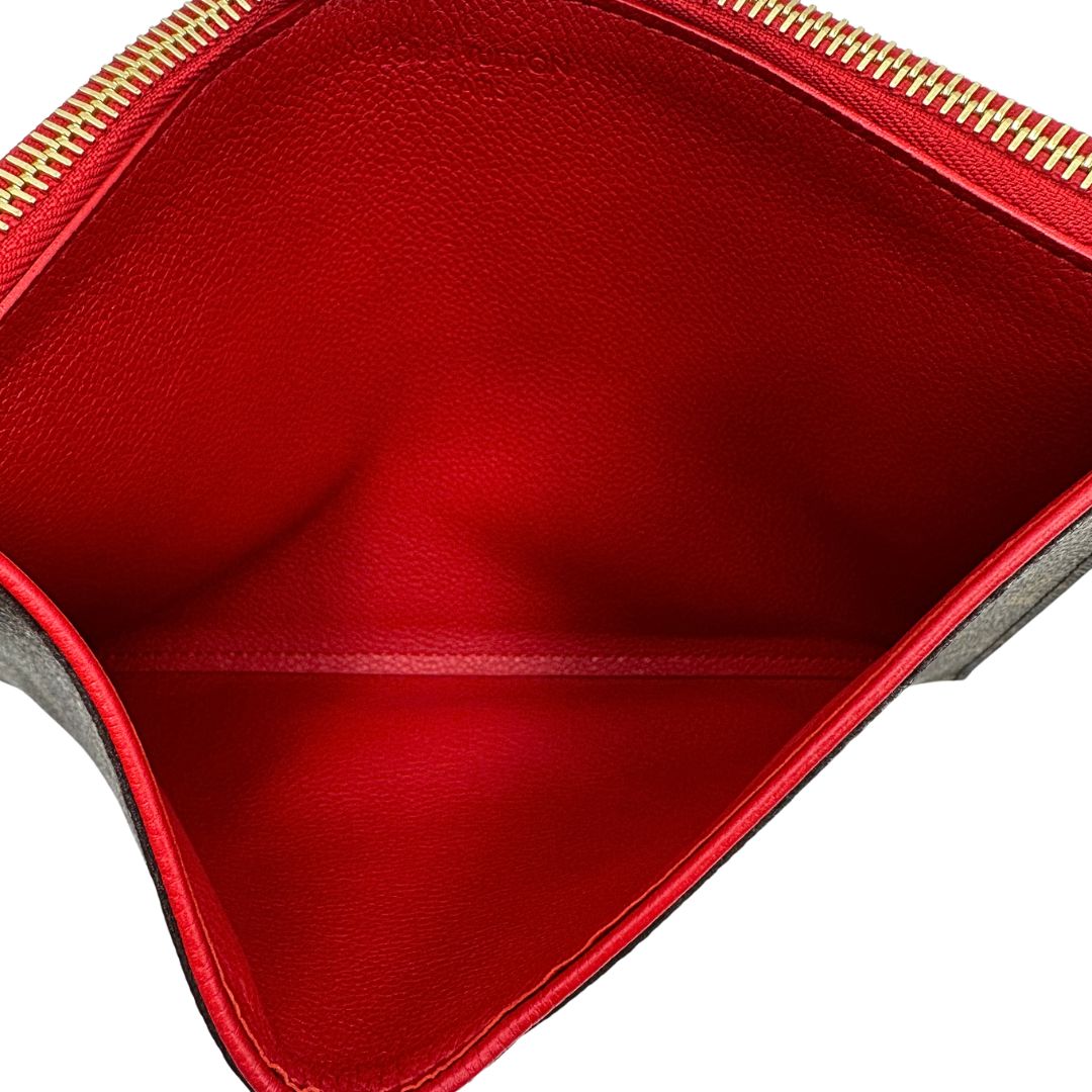 Interno di una pochette Louis Vuitton con scomparti interni portacarte, in canvas marrone monogram e dettagli rossi, con parti metalliche dorate, usata, originale, second hand, in ottime condizioni.