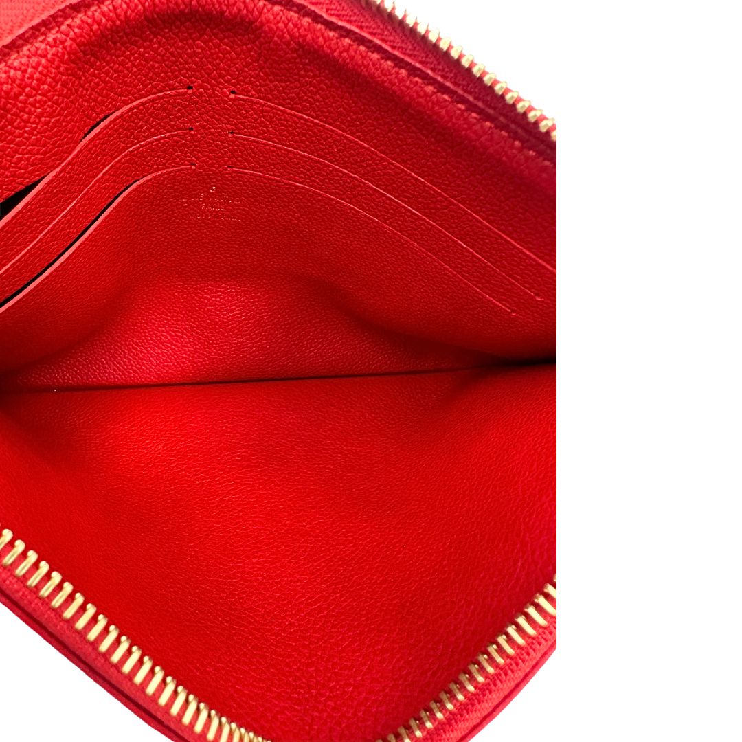 Interno di una pochette Louis Vuitton con scomparti interni portacarte, in canvas marrone monogram e dettagli rossi, con parti metalliche dorate, usata, originale, second hand, in ottime condizioni.