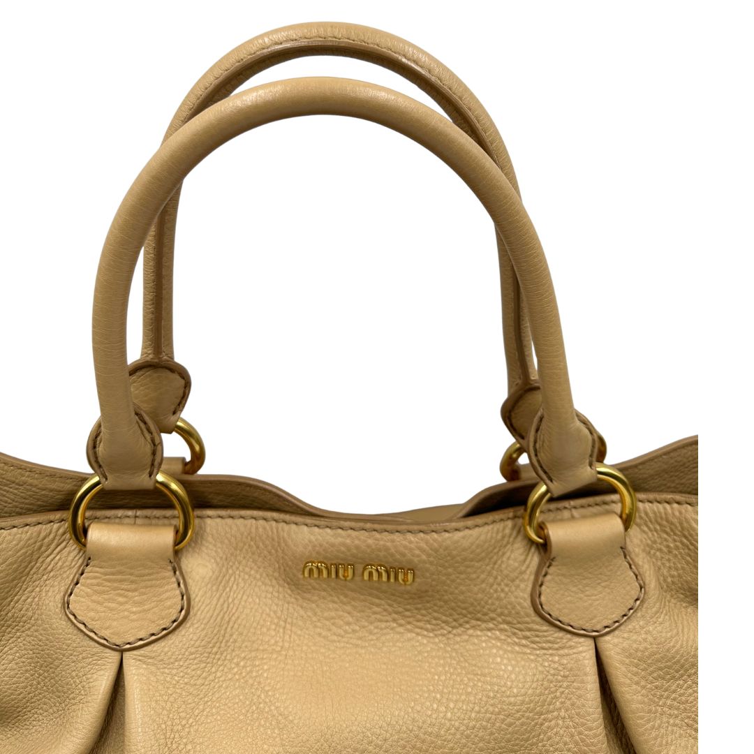 Manici, Pratica borsa Miu Miu in pelle martellata beige con parti metalliche dorate. Indossabile a spalla oppure a mano. Originale, usata, di lusso, in ottime condizioni.