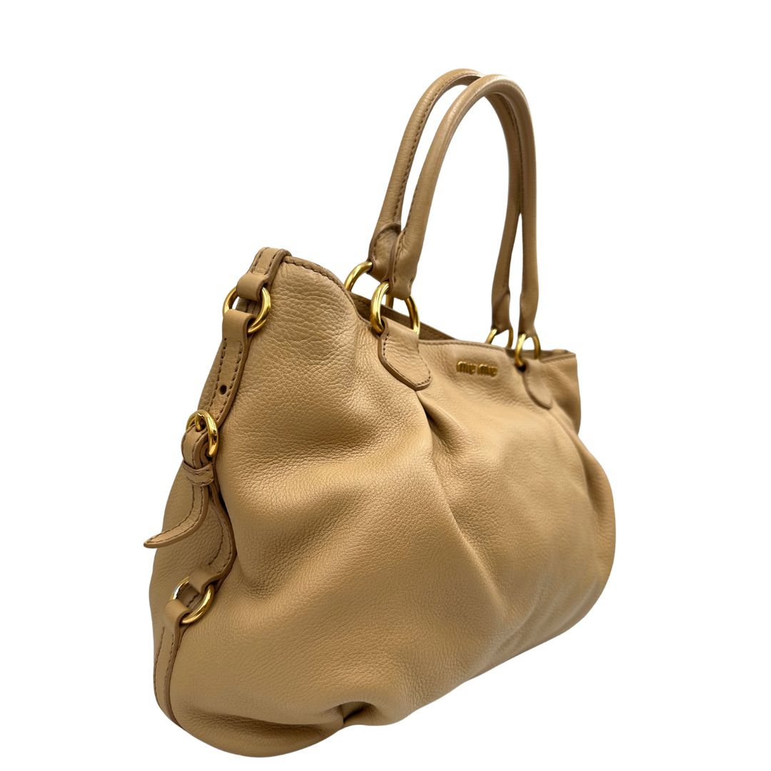 Laterale, Pratica borsa Miu Miu in pelle martellata beige con parti metalliche dorate. Indossabile a spalla oppure a mano. Originale, usata, di lusso, in ottime condizioni.
