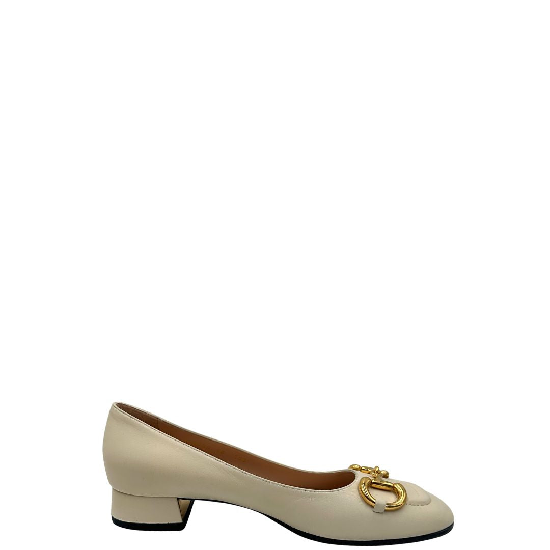 Laterale di un paio di décolleté Gucci in morbida pelle bianco latte, con iconico dettaglio Horsebit in metallo dorato.