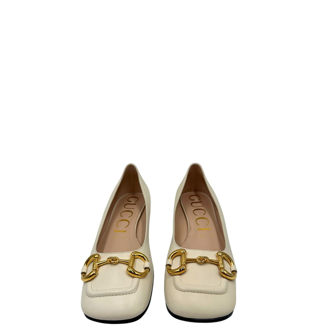 Front di un paio di décolleté Gucci in morbida pelle bianco latte, con iconico dettaglio Horsebit in metallo dorato.