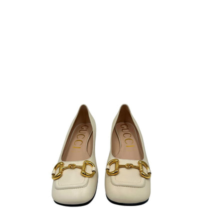 Front di un paio di décolleté Gucci in morbida pelle bianco latte, con iconico dettaglio Horsebit in metallo dorato.