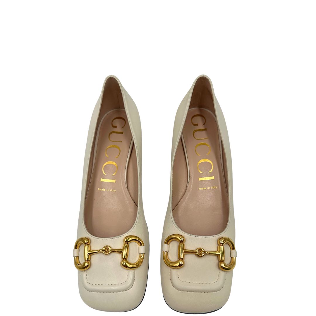 Vista superiore di un paio di décolleté Gucci in morbida pelle bianco latte, con iconico dettaglio Horsebit in metallo dorato.